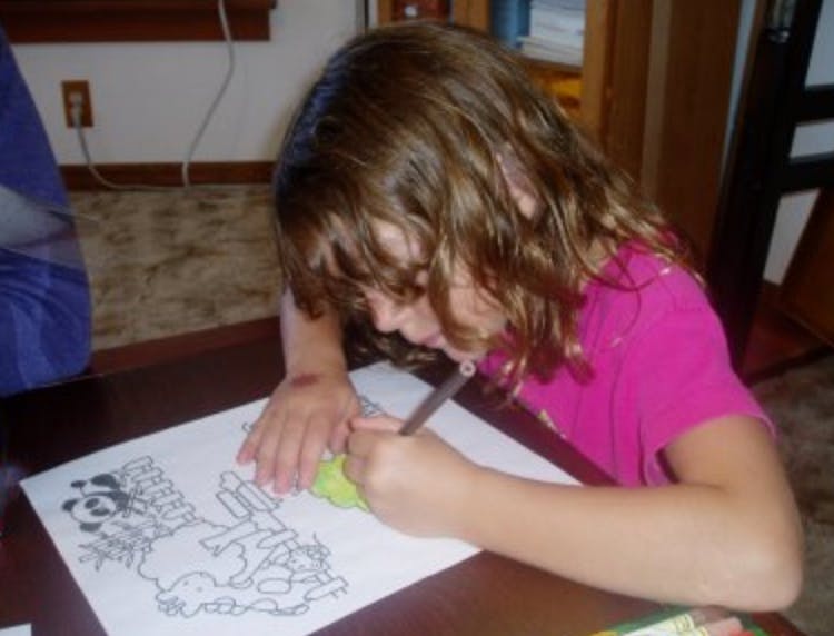 Child coloring a drawing on a table