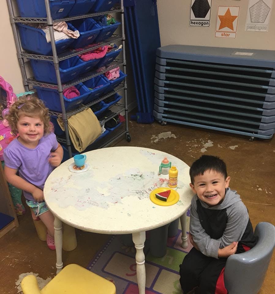 Two children sitting at a small round table in a classroom
