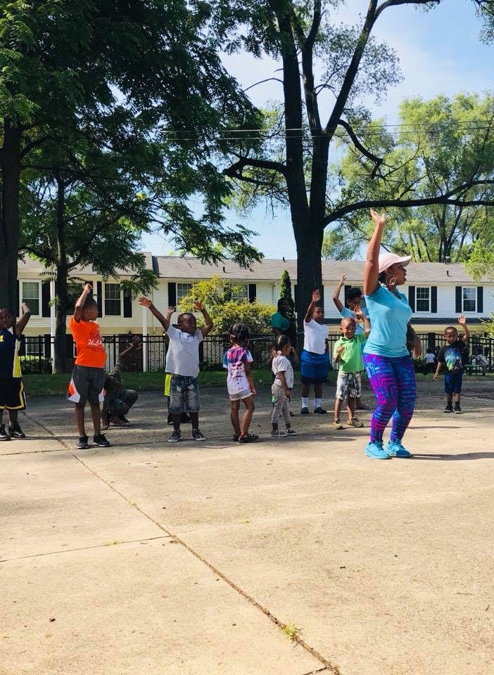 Adult and children exercising outdoors with arms raised