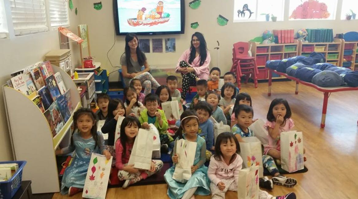 Two people with a group of children sitting on the floor in a classroom