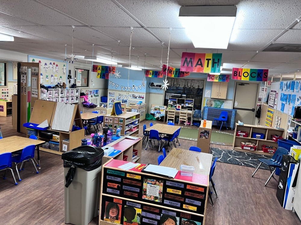 Classroom with small tables and chairs, and colorful banners for subjects