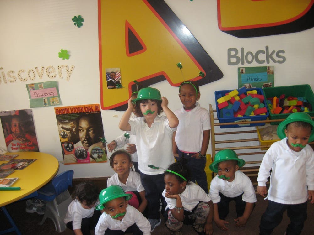Group of children wearing green hats in a classroom