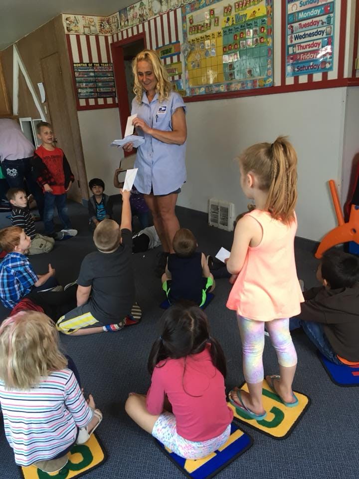 Adult person in uniform holding cards, surrounded by children in a classroom