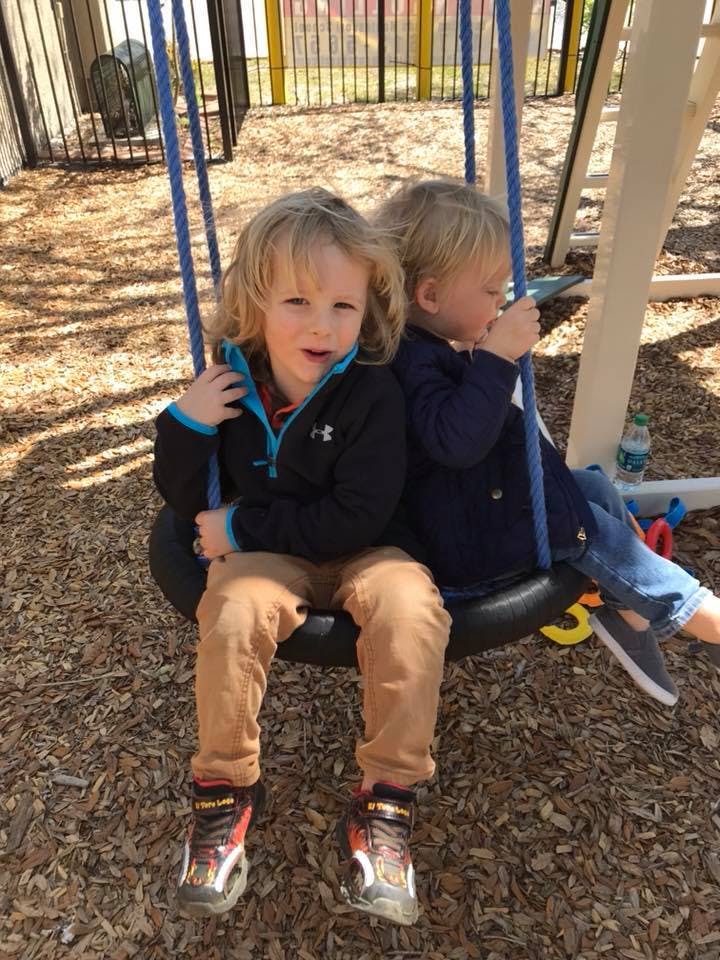 Two children sitting on a tire swing at a playground
