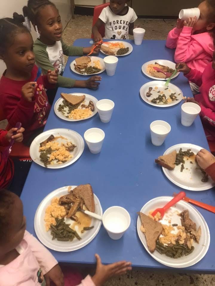 Children eating meals at a blue table