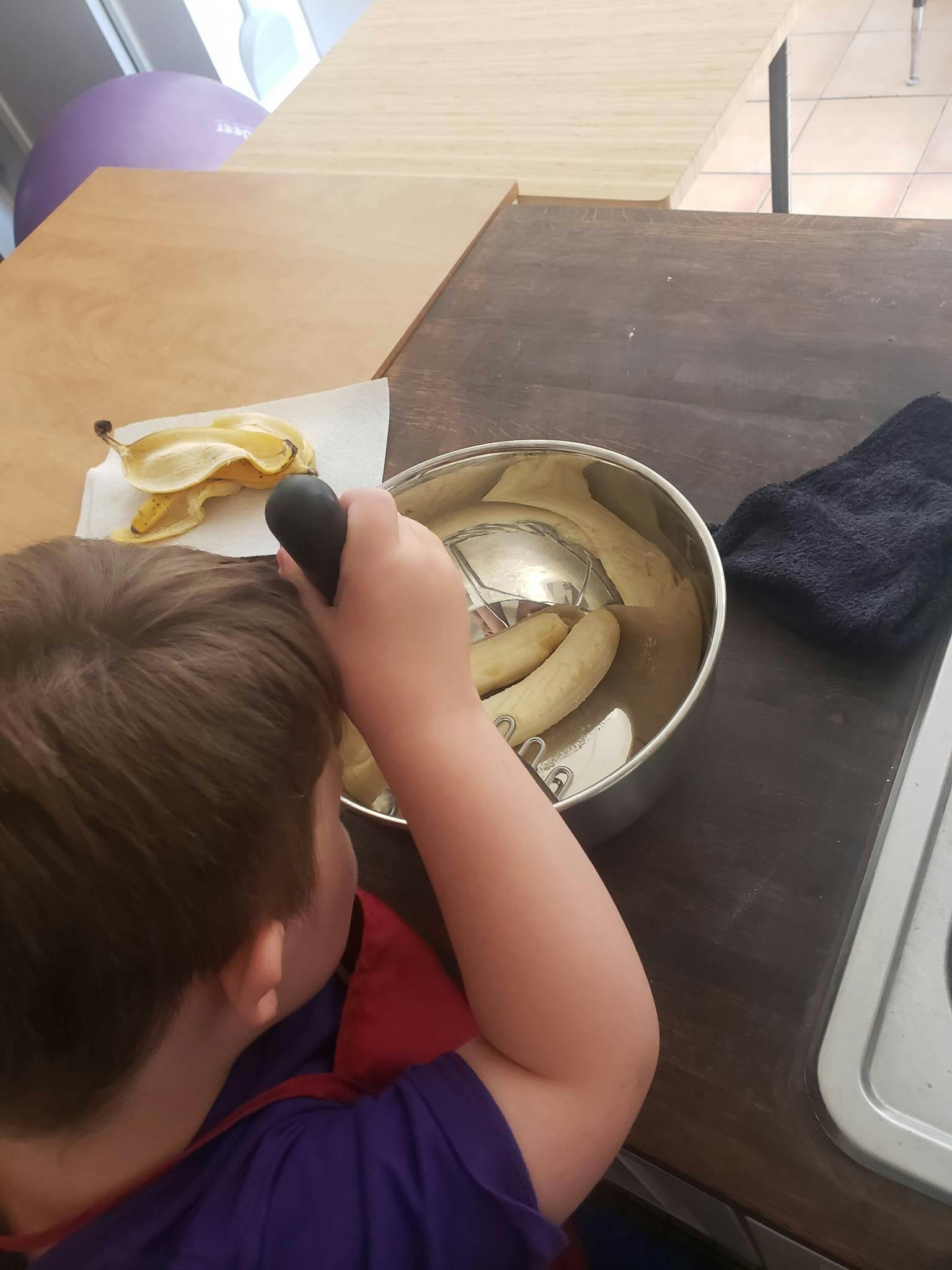 Child mashing bananas in a bowl