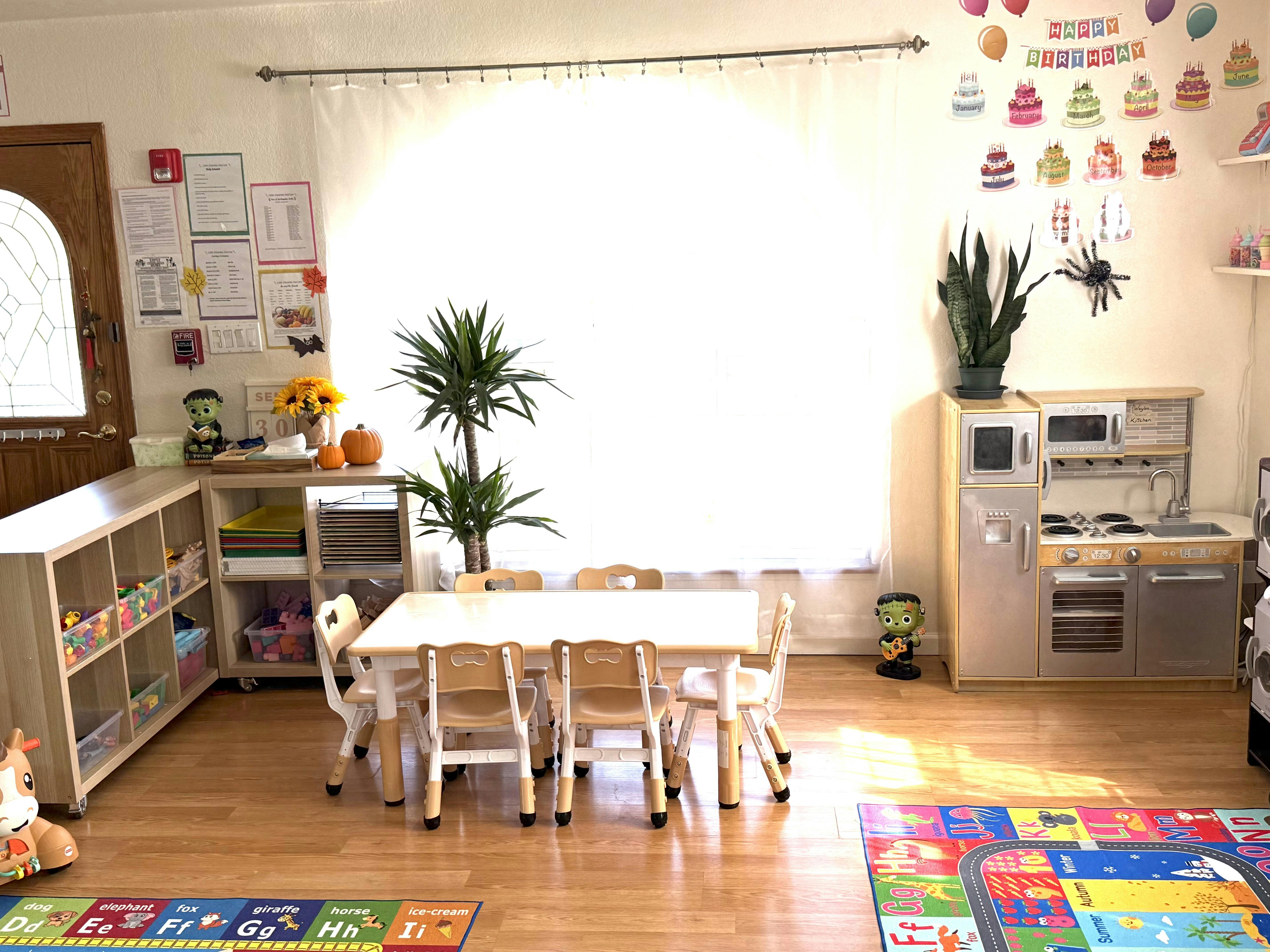 Childcare room with a small table and chairs and a play kitchen