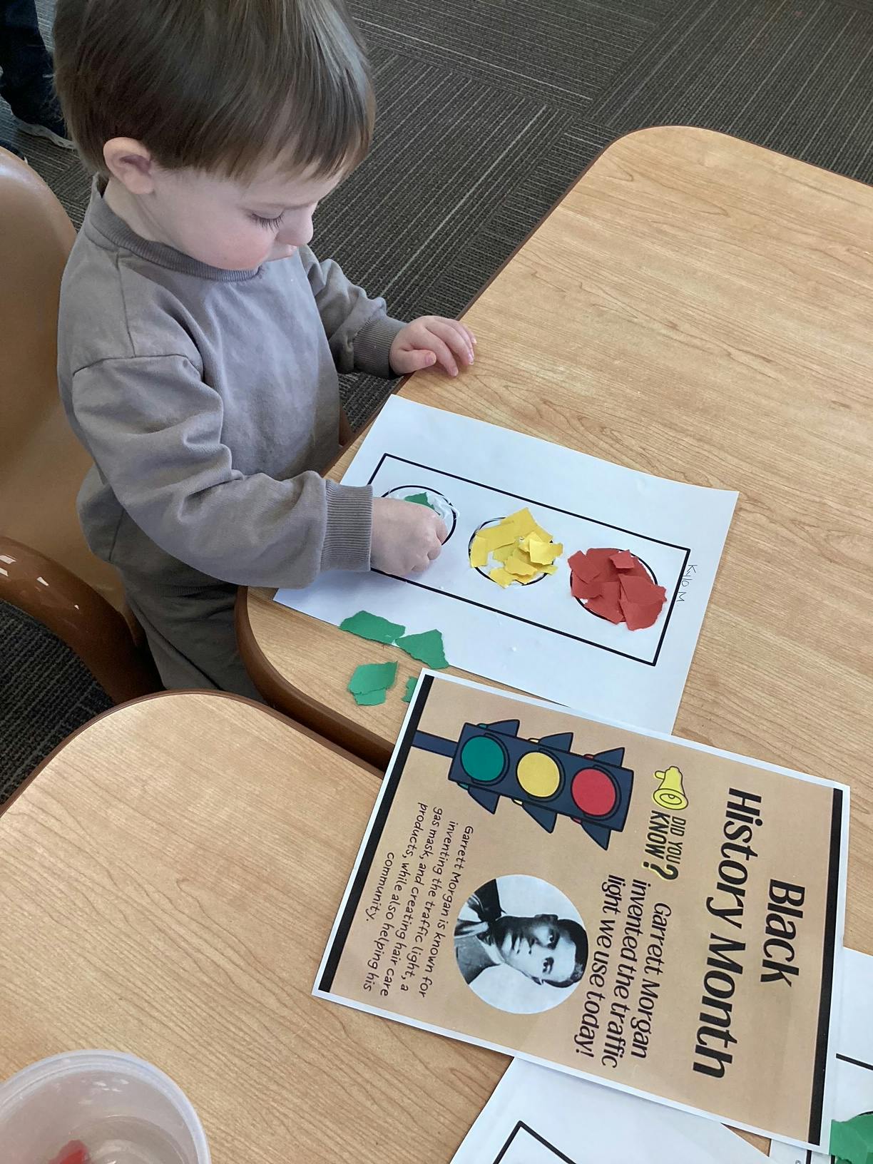 Child crafting a traffic light on a table next to a Black History Month sign