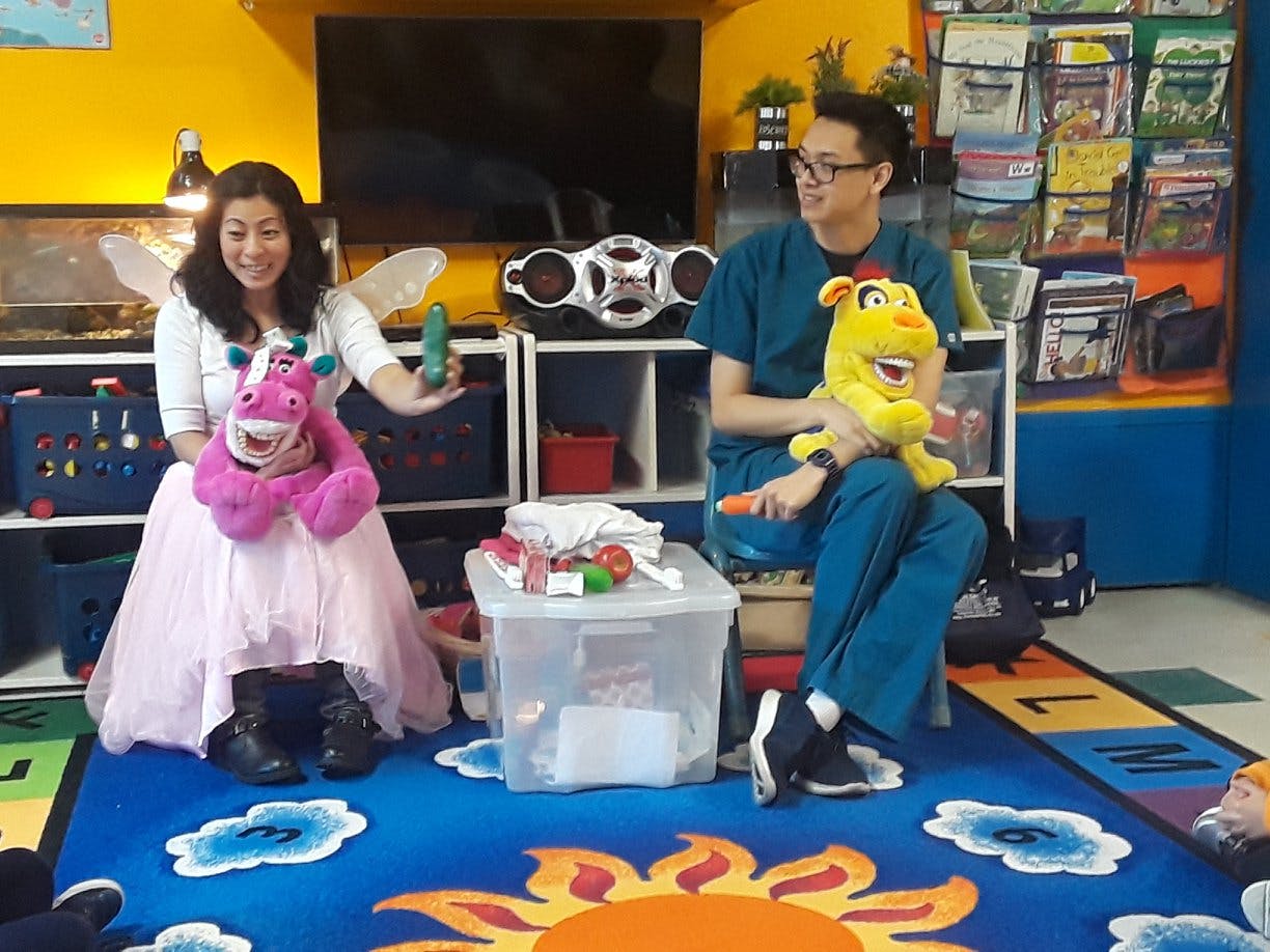 Two people sitting on a rug with stuffed animals