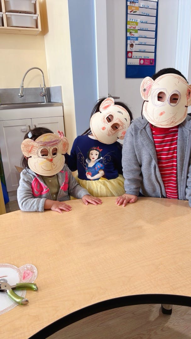 Three children wearing animal masks sitting at a table