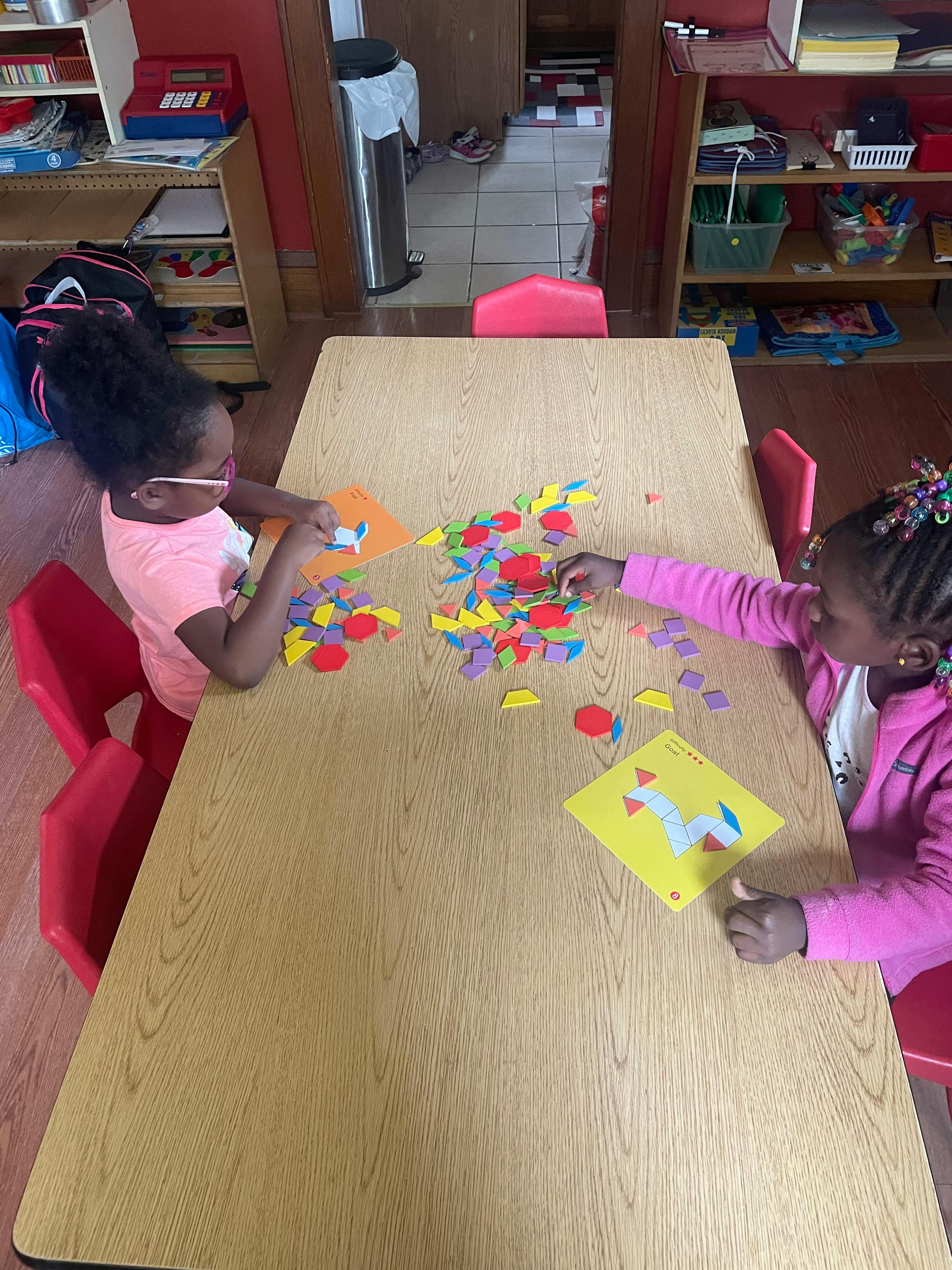 Two children playing with colorful shapes at a table