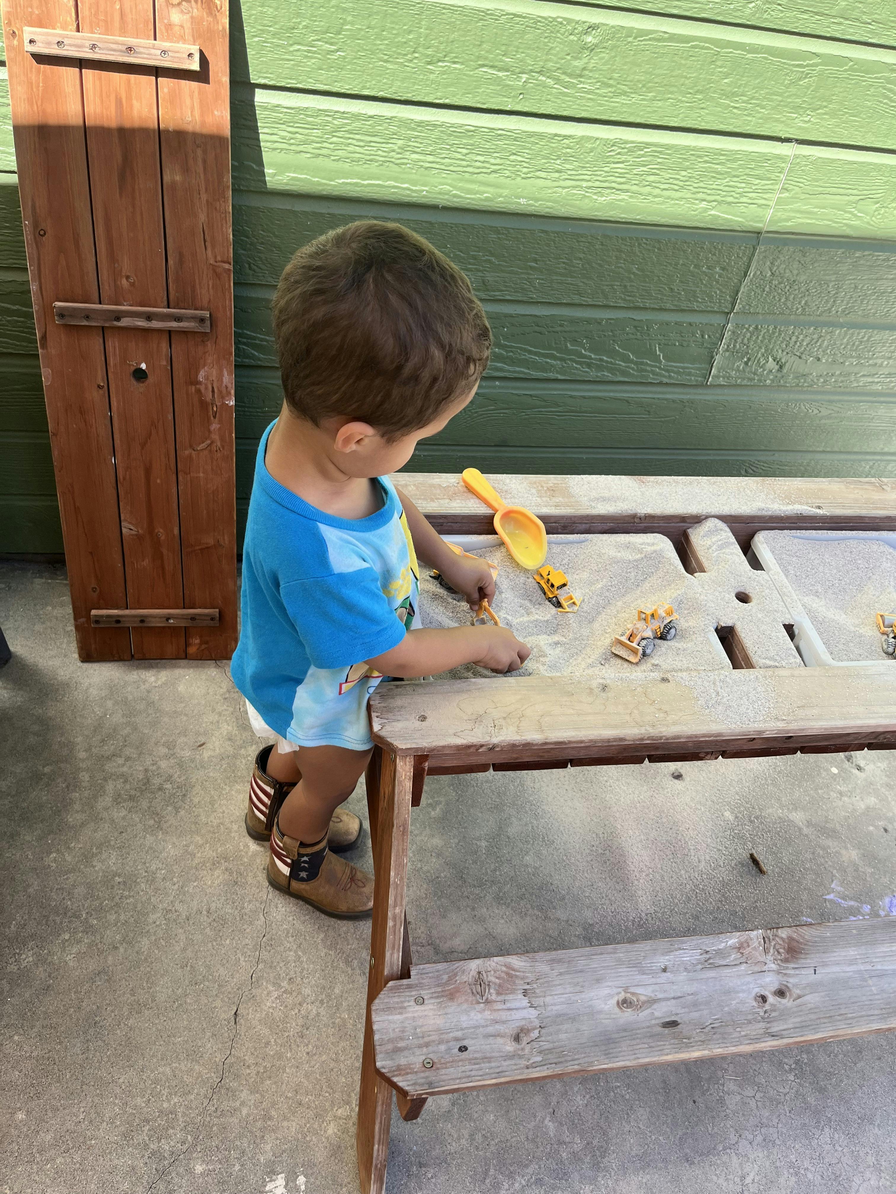Child playing with toys at a sand and water table