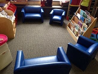 Four blue chairs and a bookshelf in a classroom