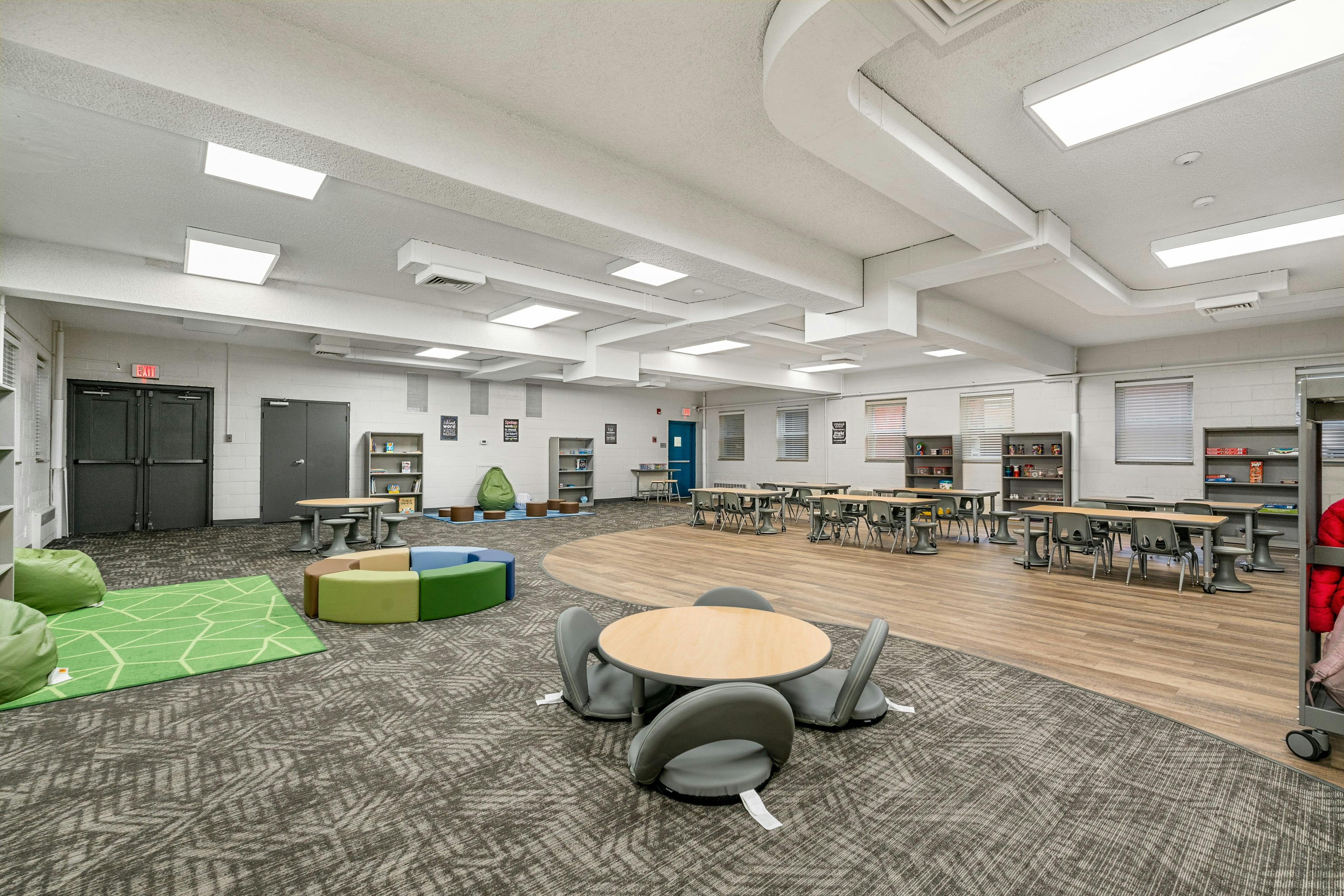 Empty classroom with tables and chairs on carpet and wood flooring