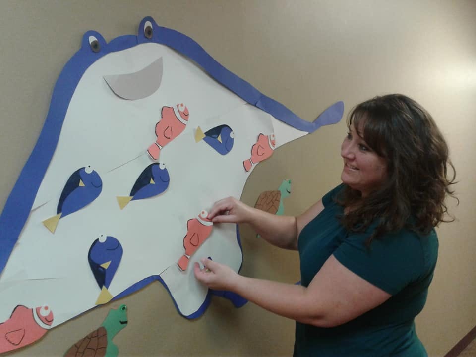 Person placing a fish cutout on a large stingray cutout