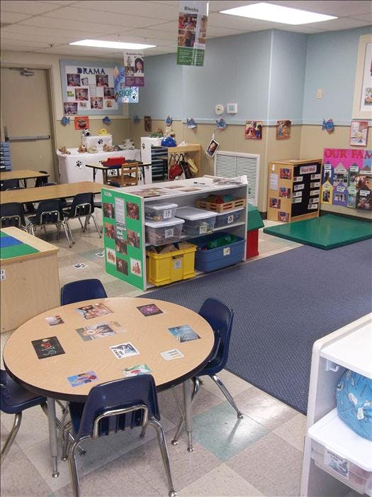 Classroom with tables, chairs, and shelves full of learning materials