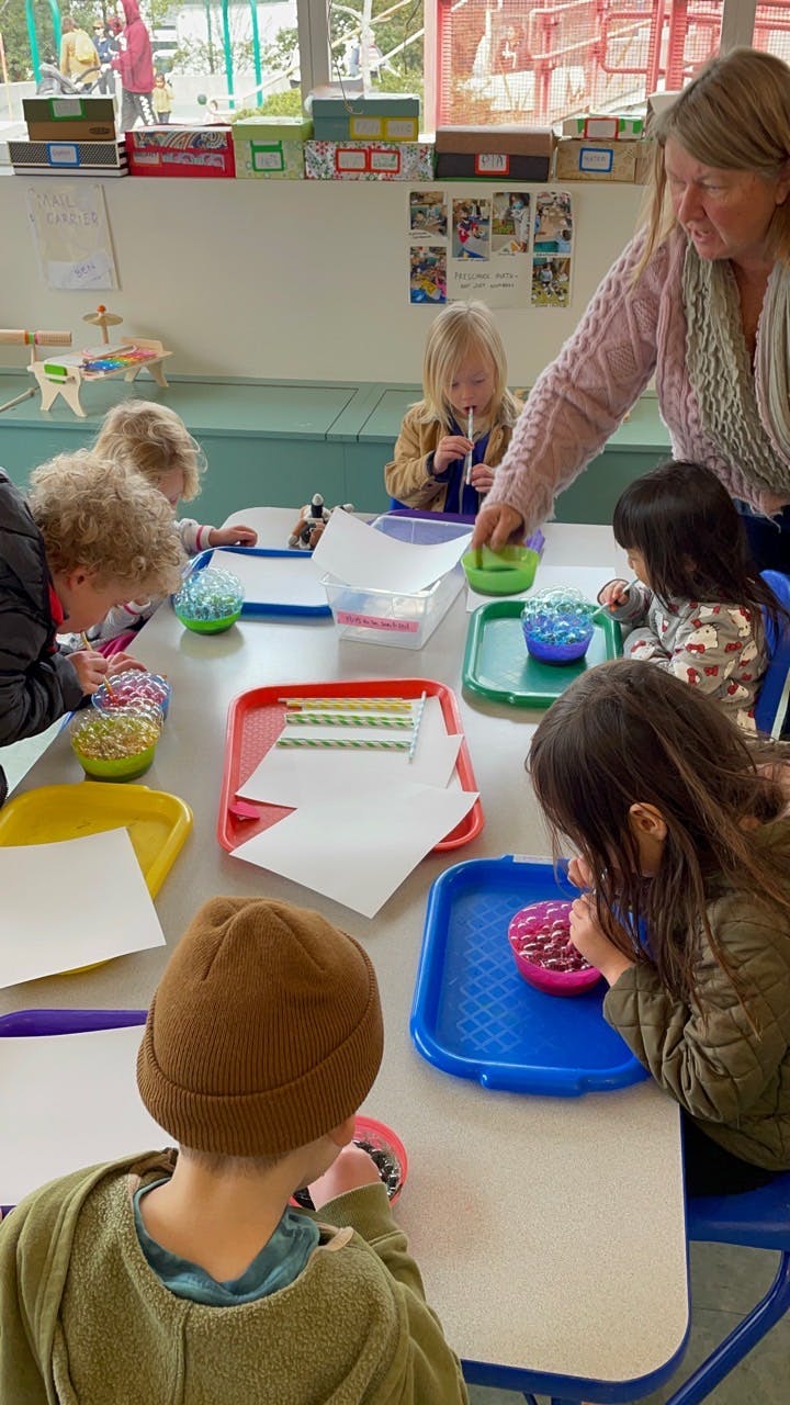 Adult and children at a table doing an art activity