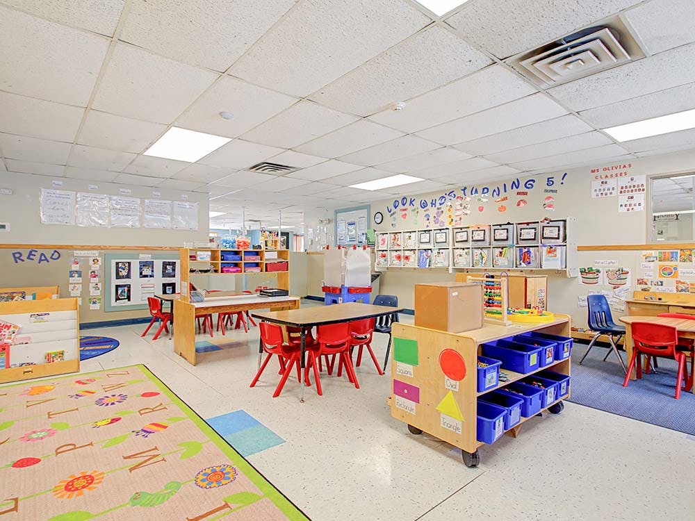 Empty colorful preschool classroom with small tables and chairs