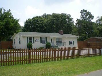 White house with green shutters and a brown picket fence