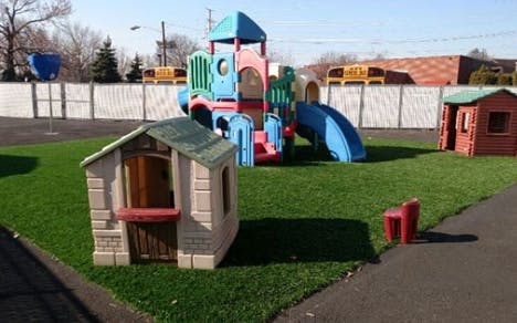 Playground with colorful play structure, slides, and playhouses on grass