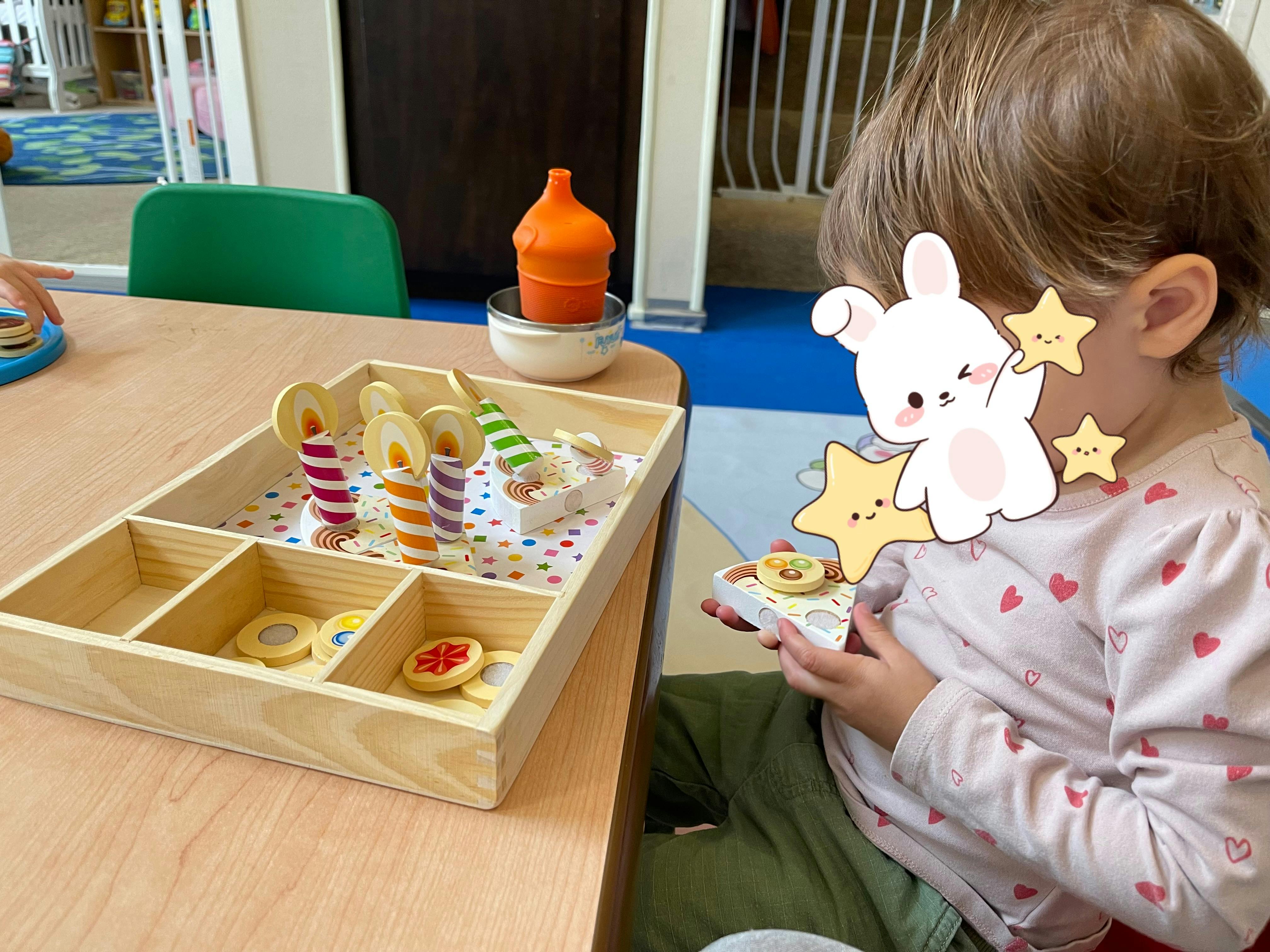 Child playing with toy food and a wooden tray with toy candles