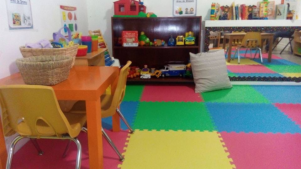 Playroom with colorful floor mats, small tables, and shelves with toys