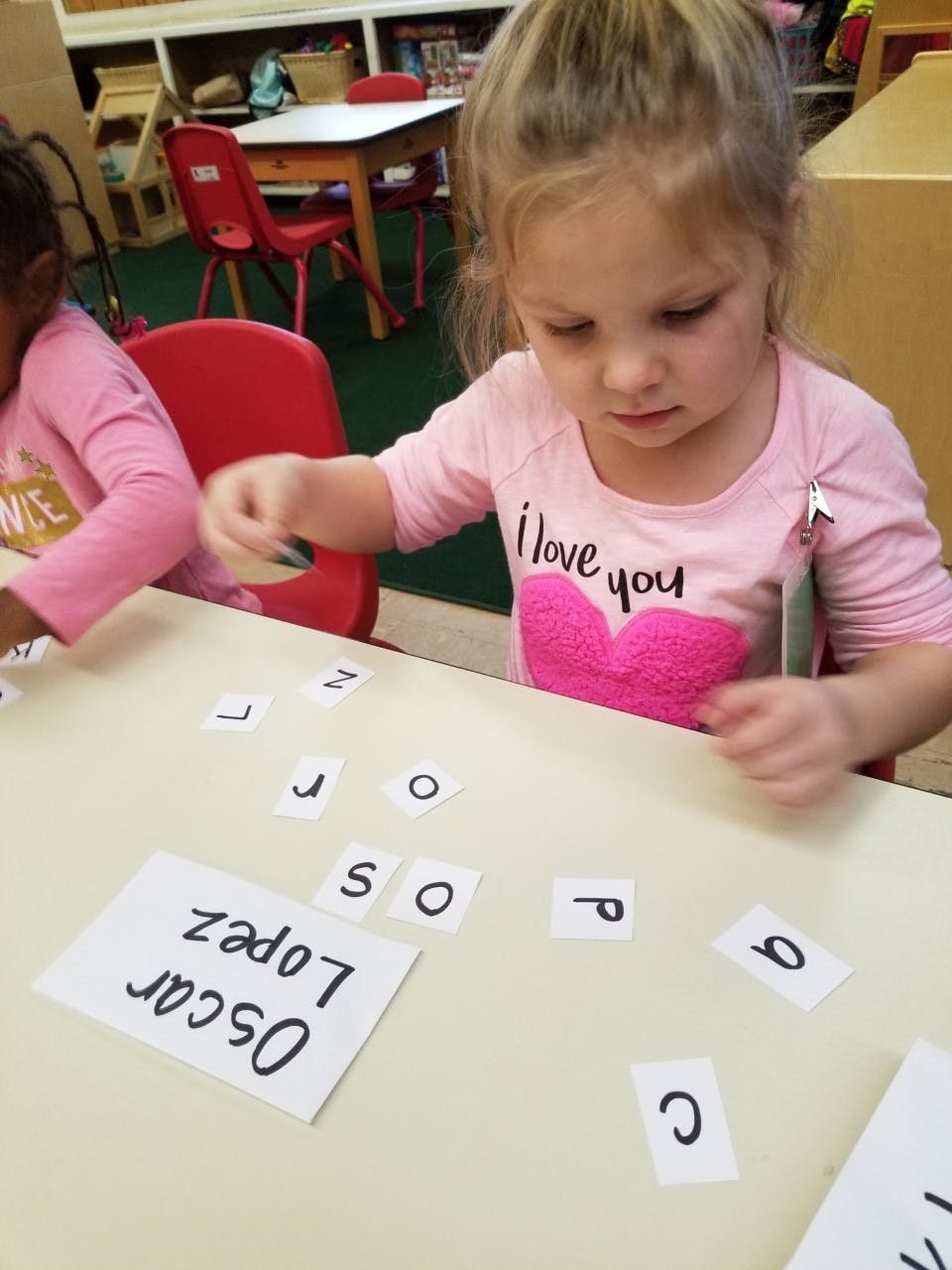 Child playing with letter cards on a table
