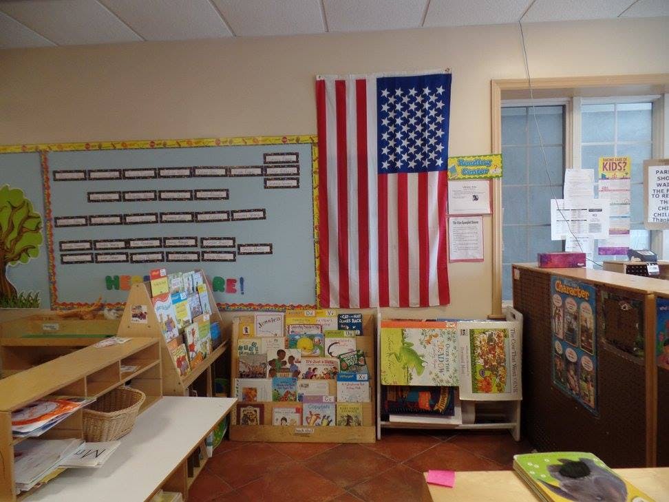 American flag hanging on a wall in a classroom with bulletin boards and bookshelves