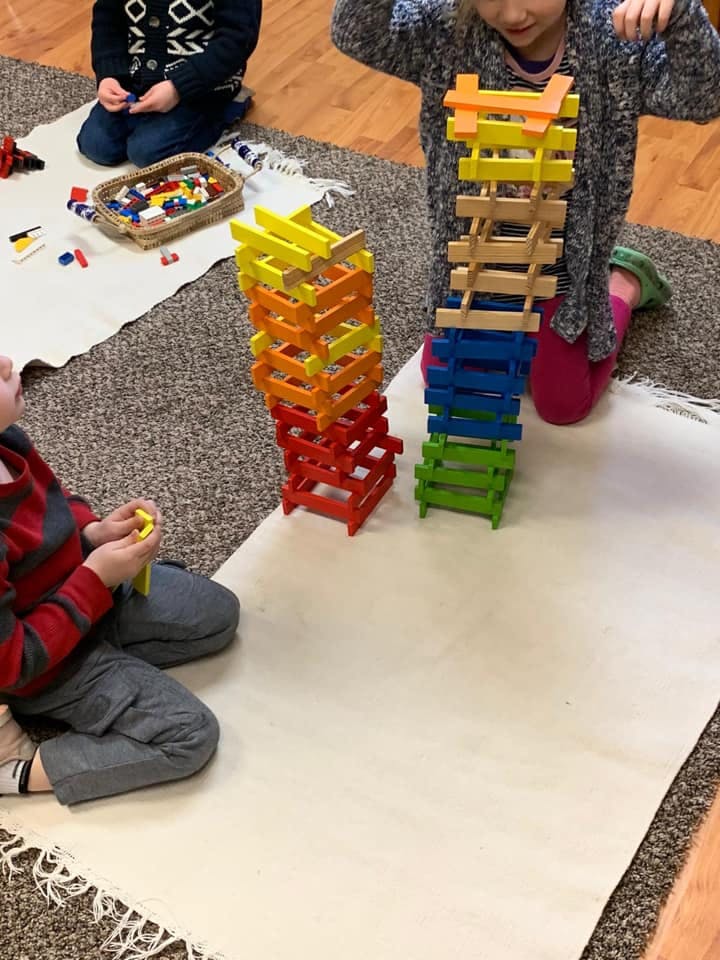 Children playing with colorful stacking blocks on a rug