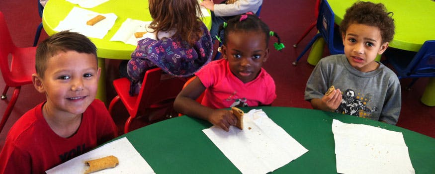 Three children at a table with paper