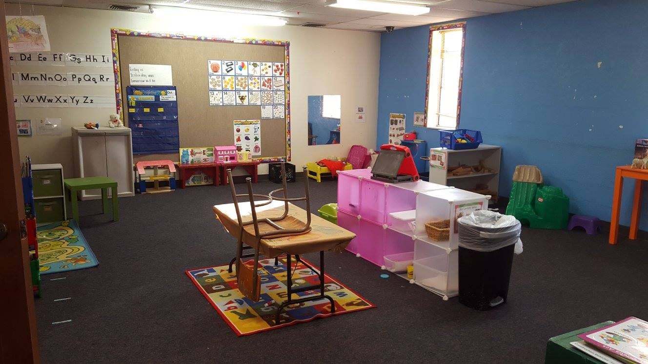 Empty classroom with tables, chairs, and colorful rugs