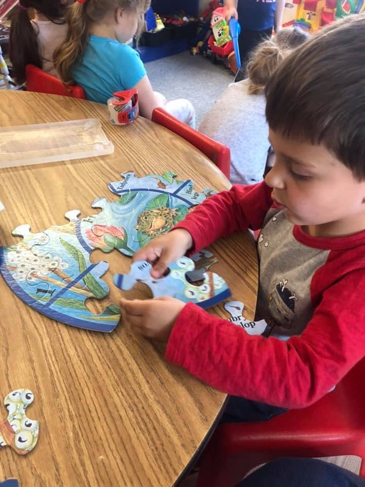 Child assembling a puzzle on a wooden table