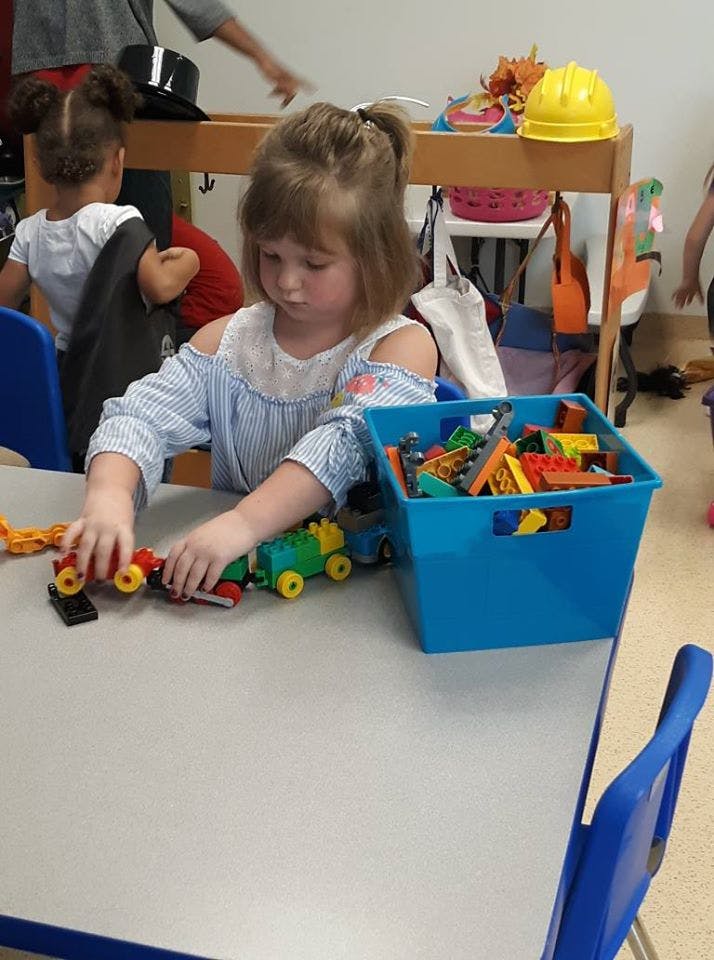 Child playing with toy train cars at a table