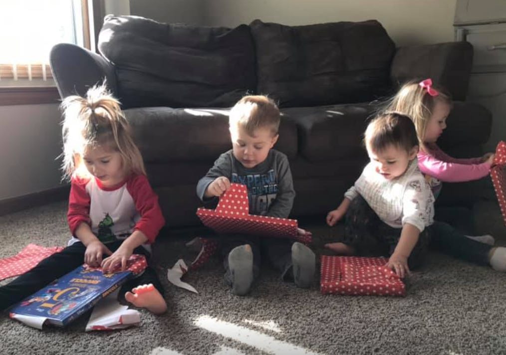 Four children on a carpeted floor with wrapped gifts