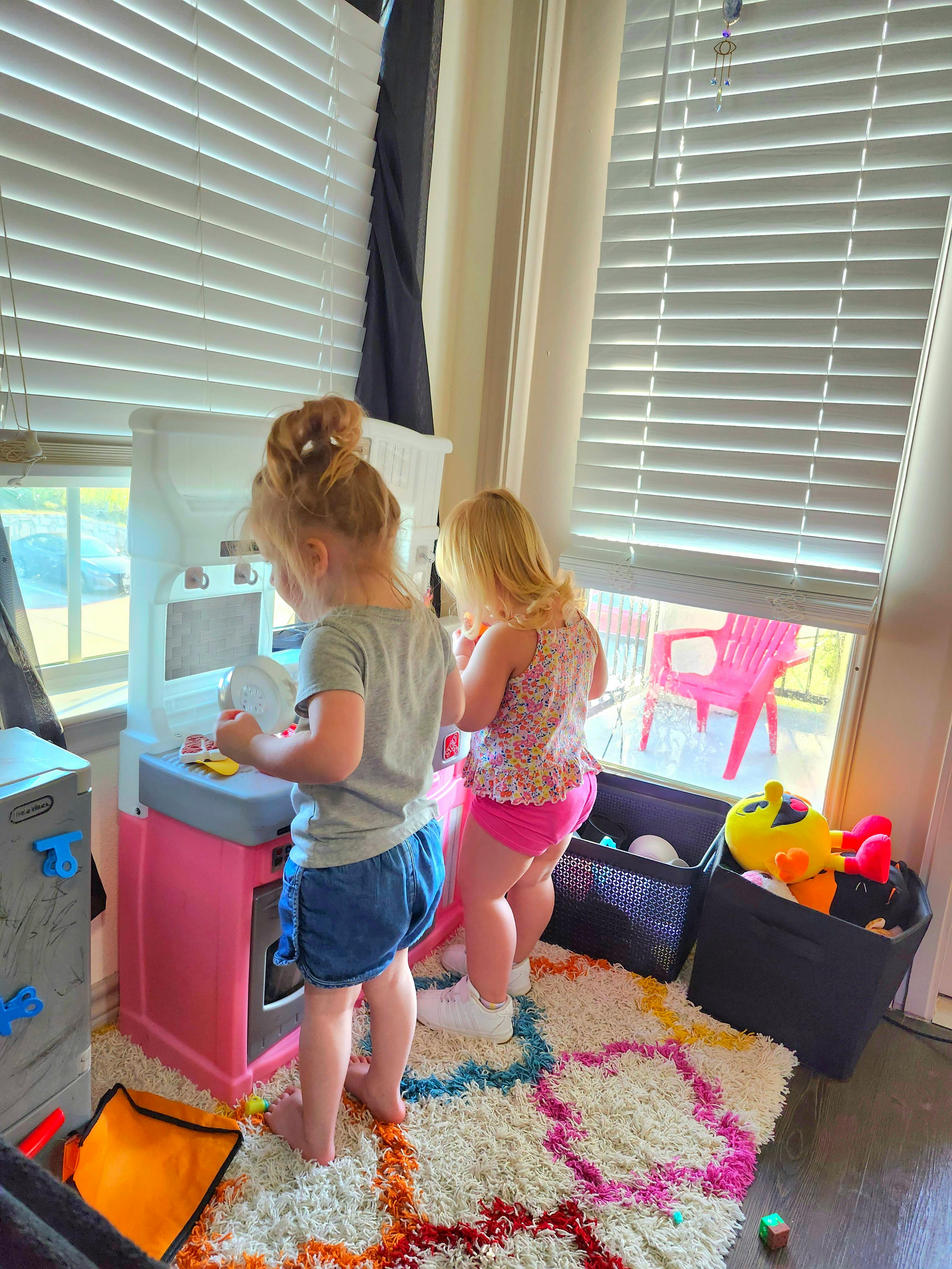Two children playing with a toy kitchen set