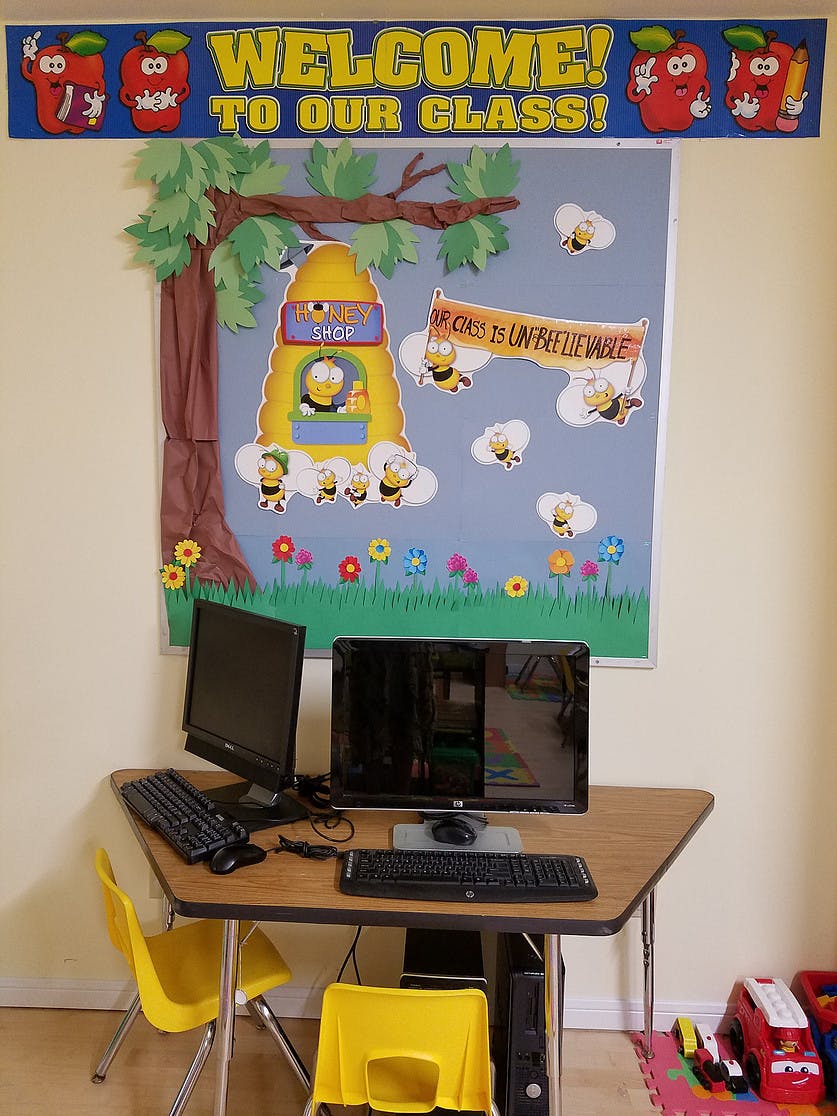 Classroom with computers on a desk and a bulletin board with bee decorations
