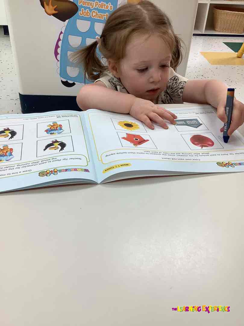 Child coloring in a workbook at a table