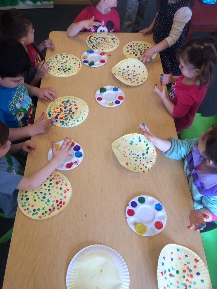 Children painting paper plates at a table