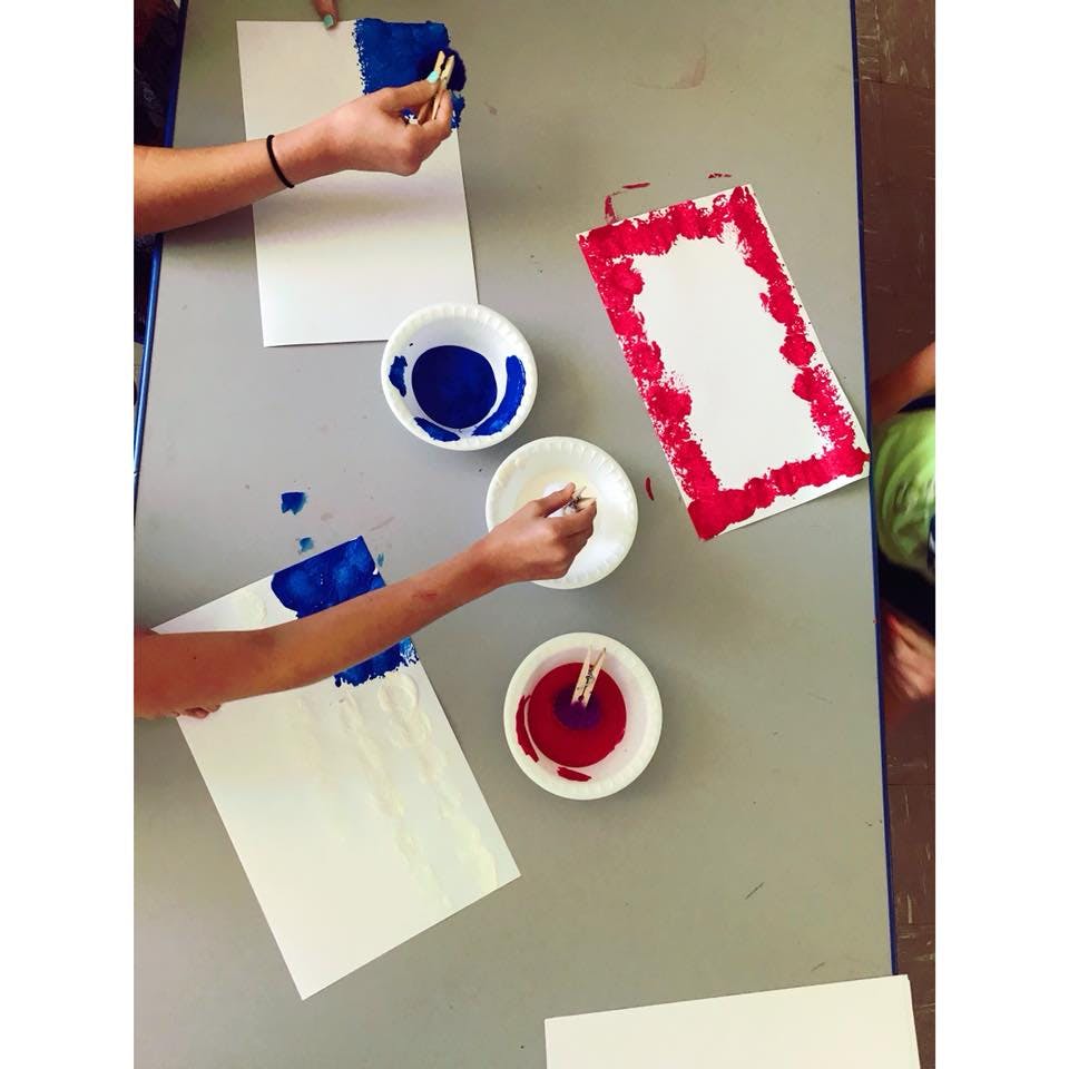 People painting with blue and red paint on white paper