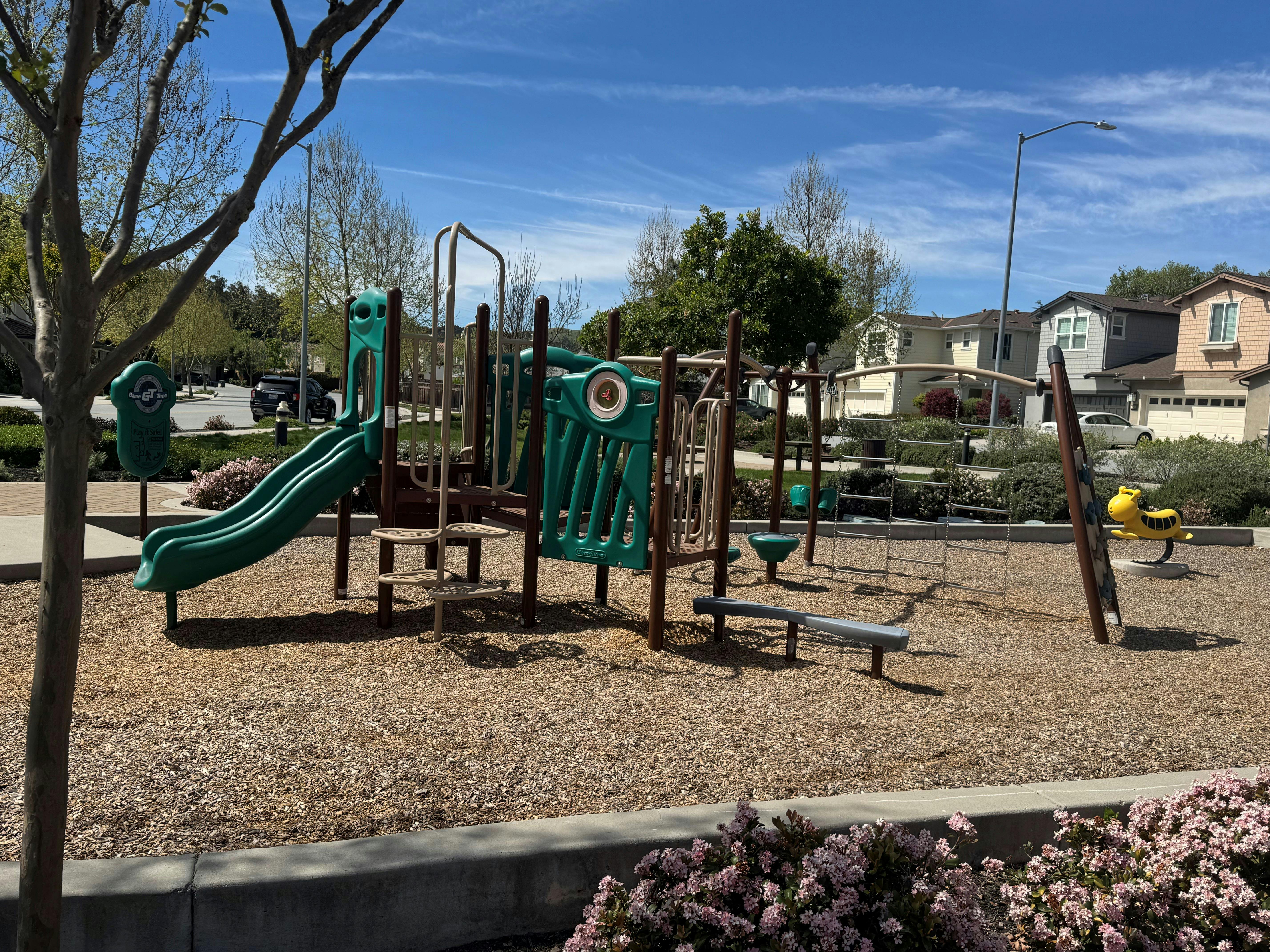 Playground structure with slides, climbing bars, and a yellow spring rider