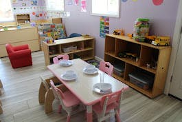 Child's classroom with small table and chairs, shelves with toys