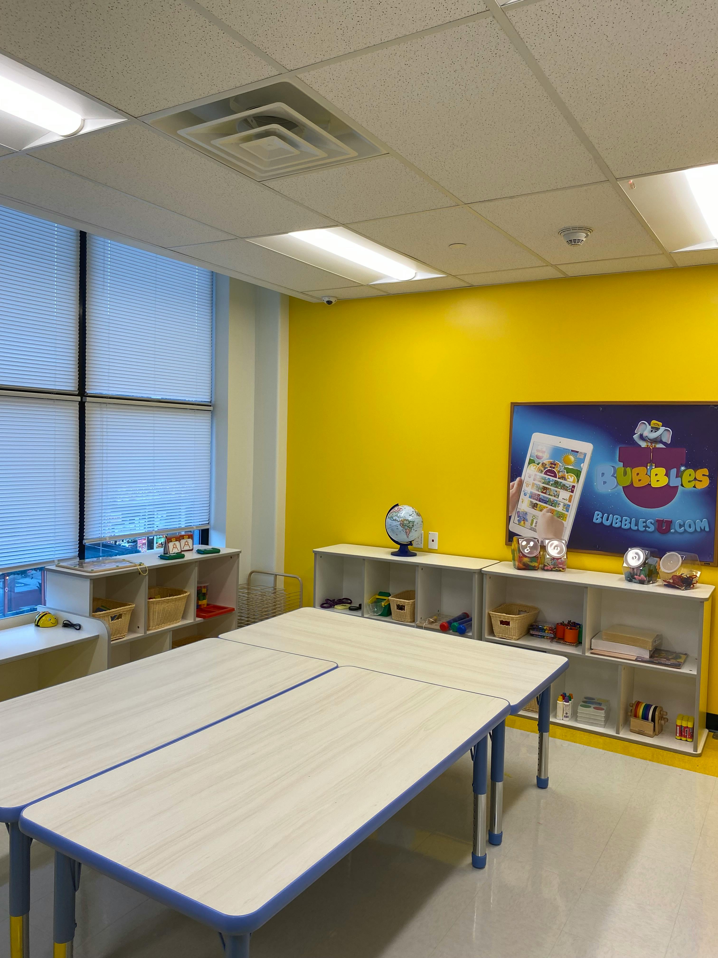 Classroom with tables, shelves, and a yellow wall