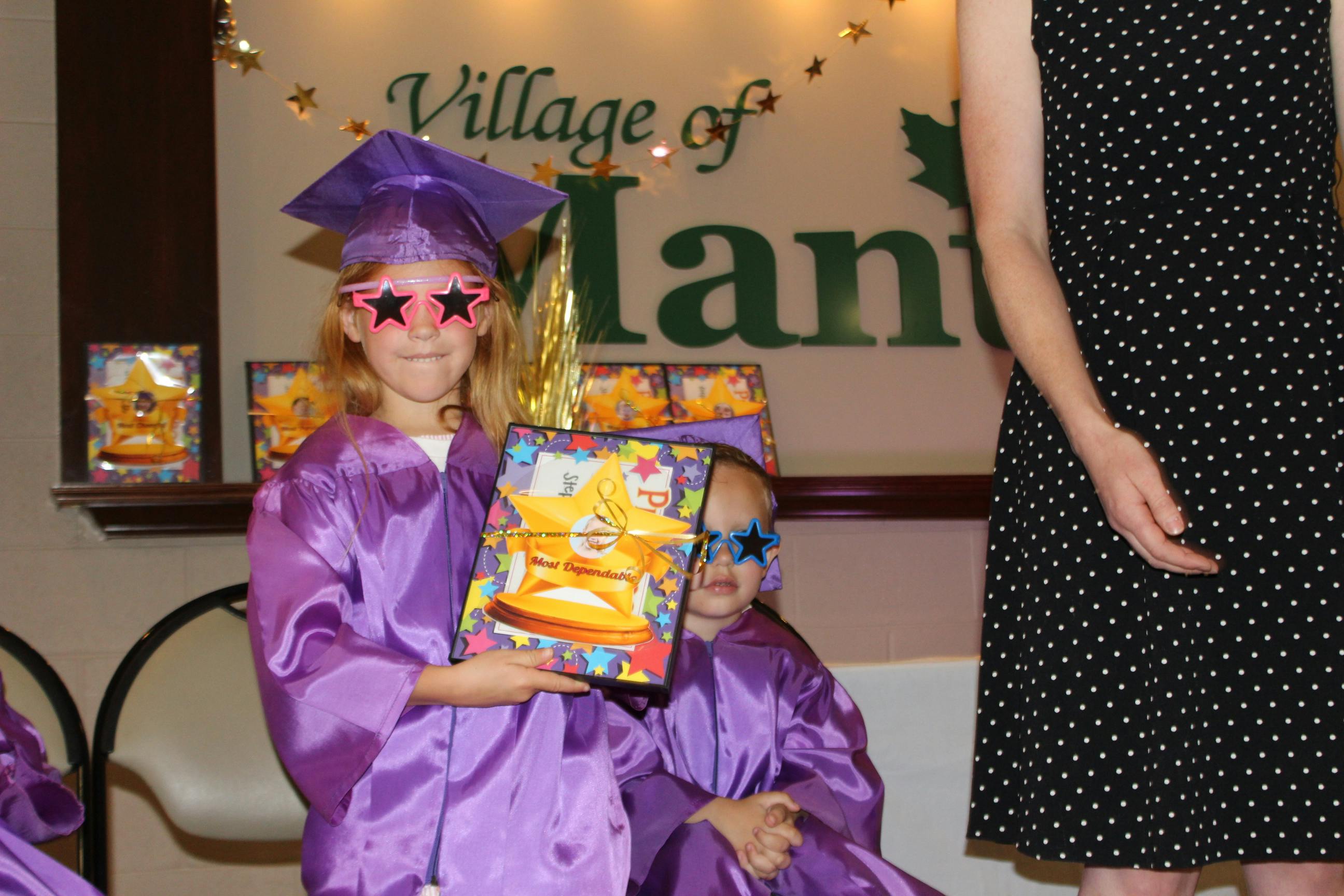 Child in graduation cap and gown holding a certificate