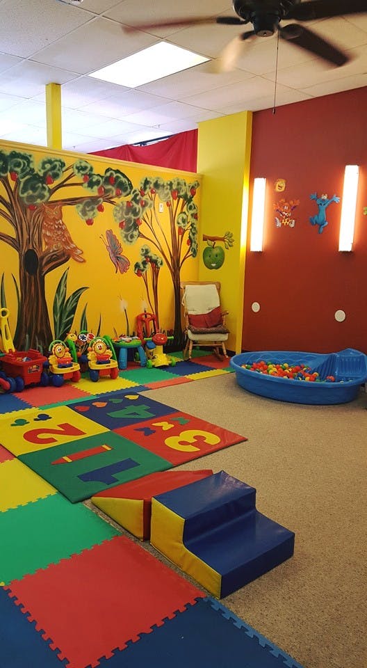Playroom with colorful floor mats, toys, and a ball pit
