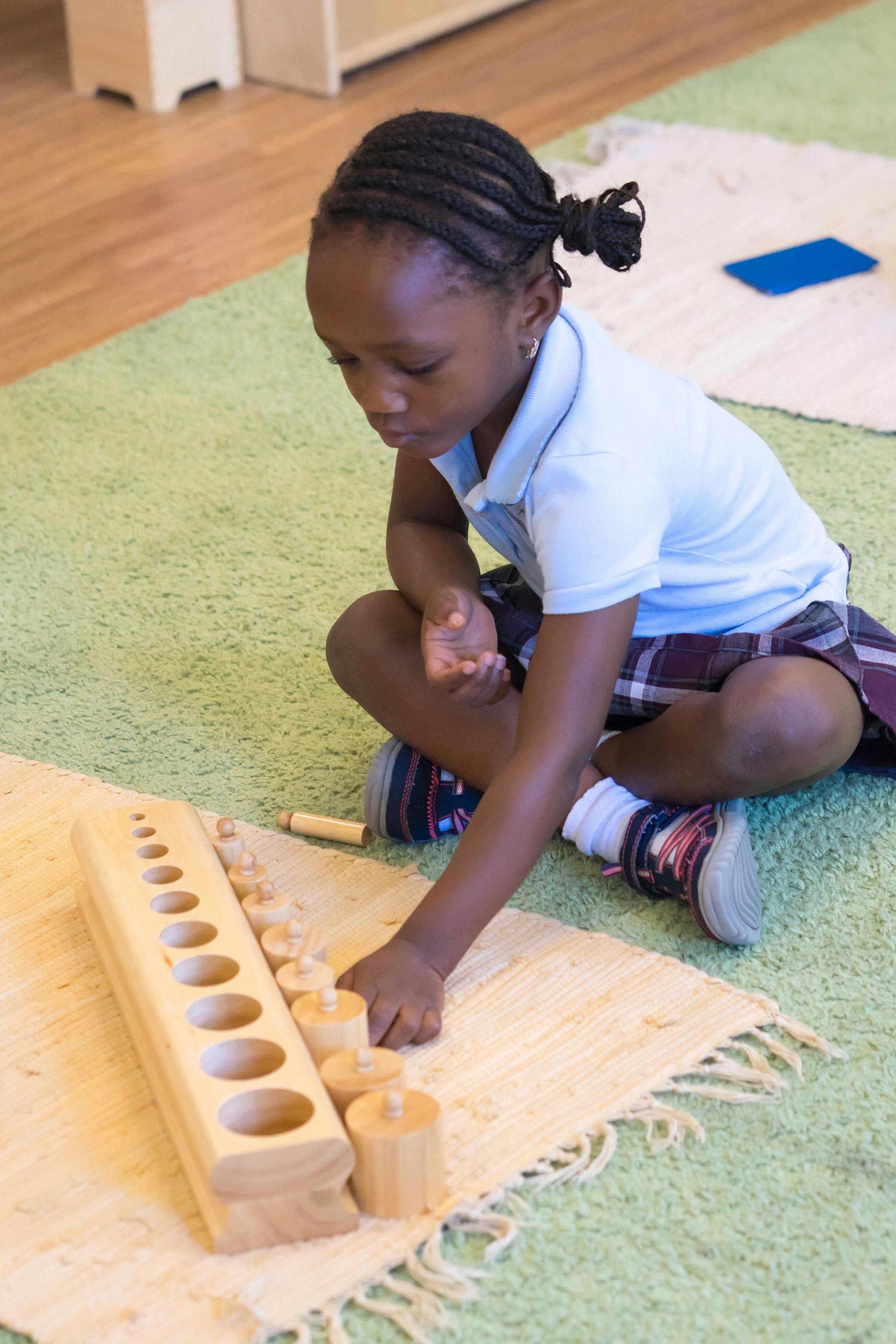 Child playing with wooden cylinder blocks on a rug