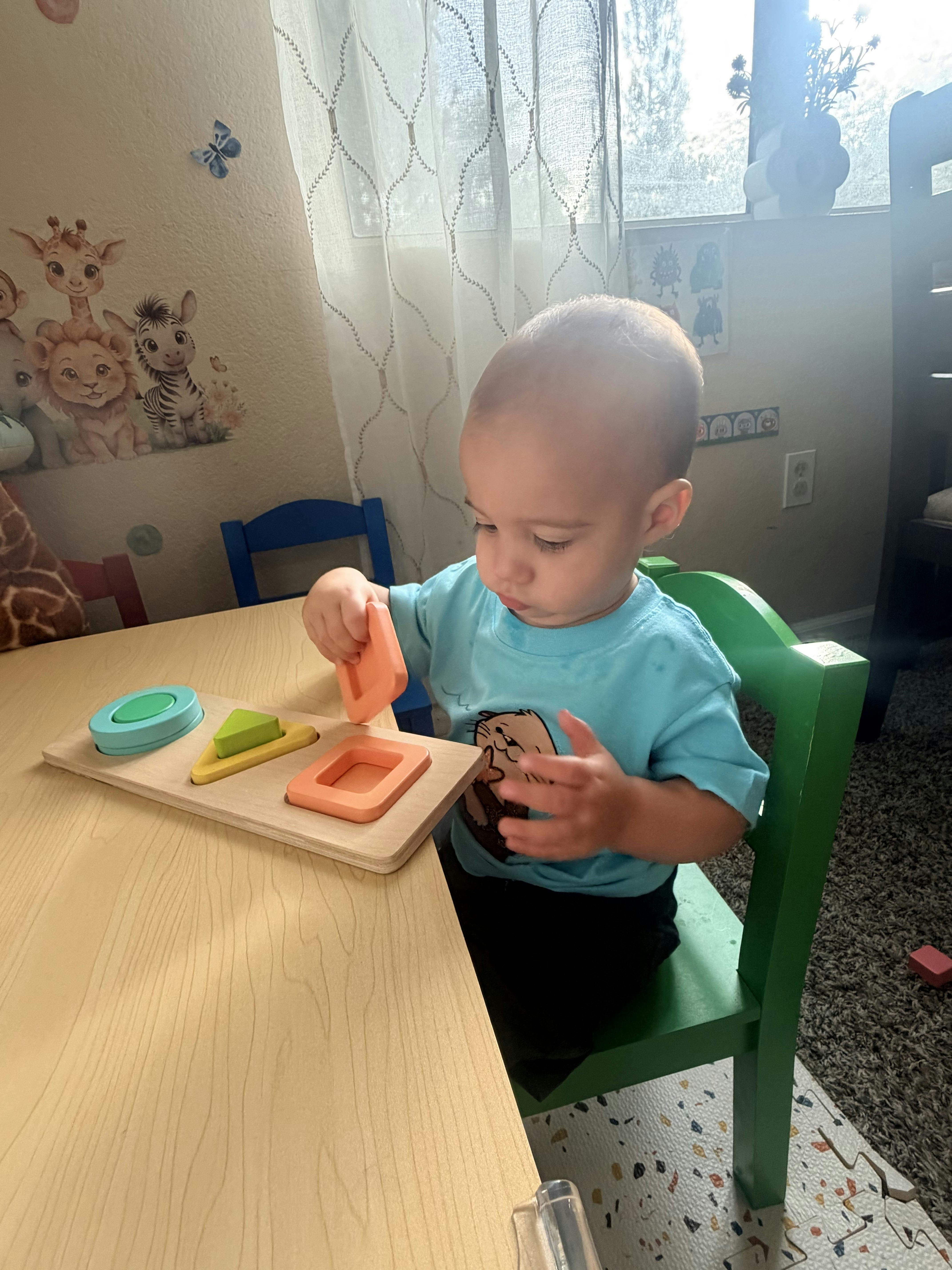 Child sitting at a table playing with a shape sorting toy