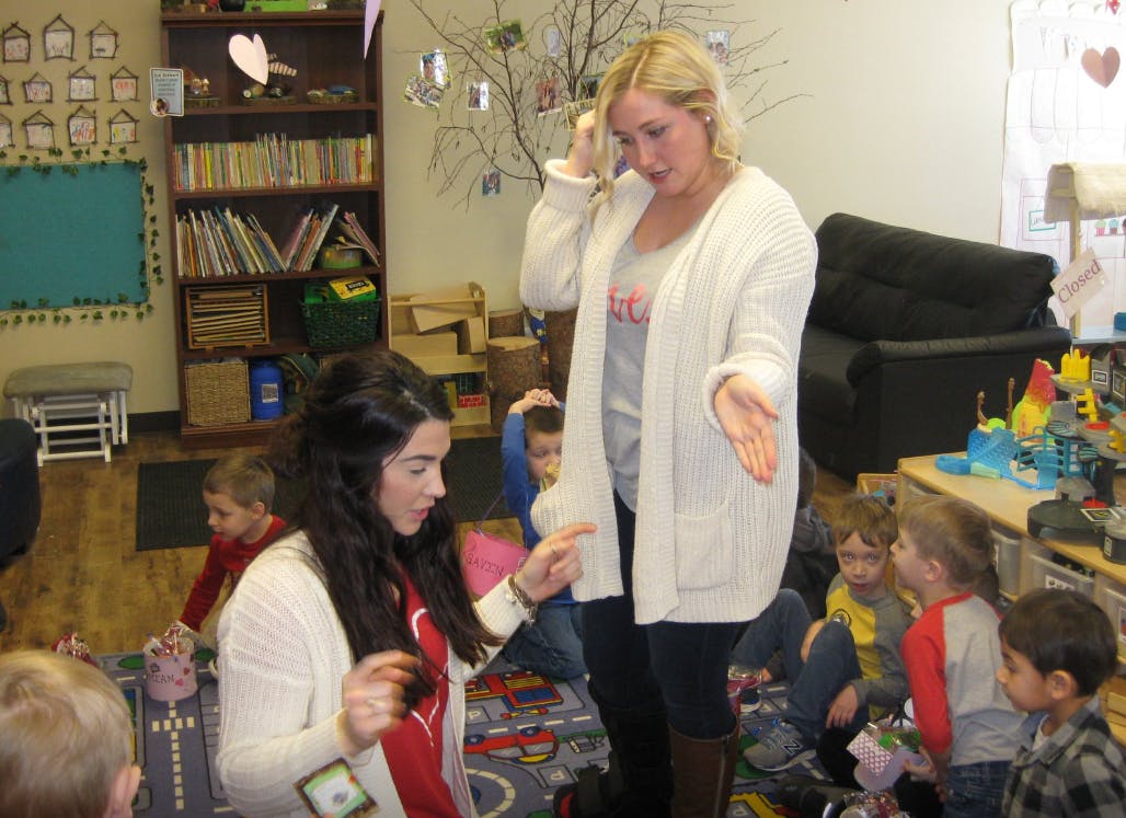 Two people interacting with children in a classroom