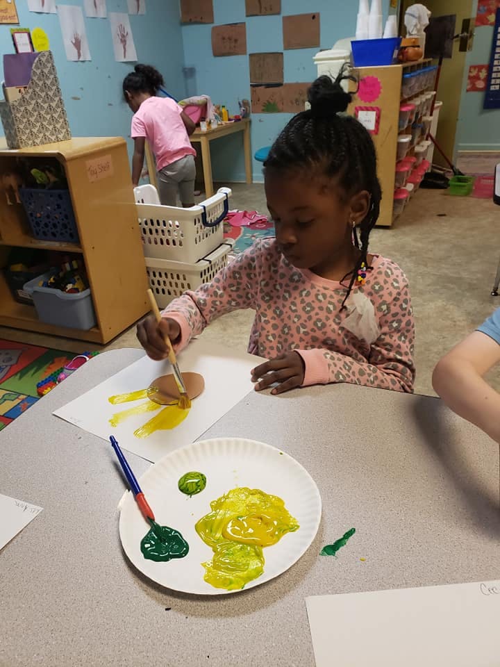 Child painting at a table in a classroom