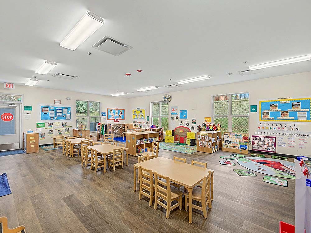 Empty preschool classroom with small tables and chairs