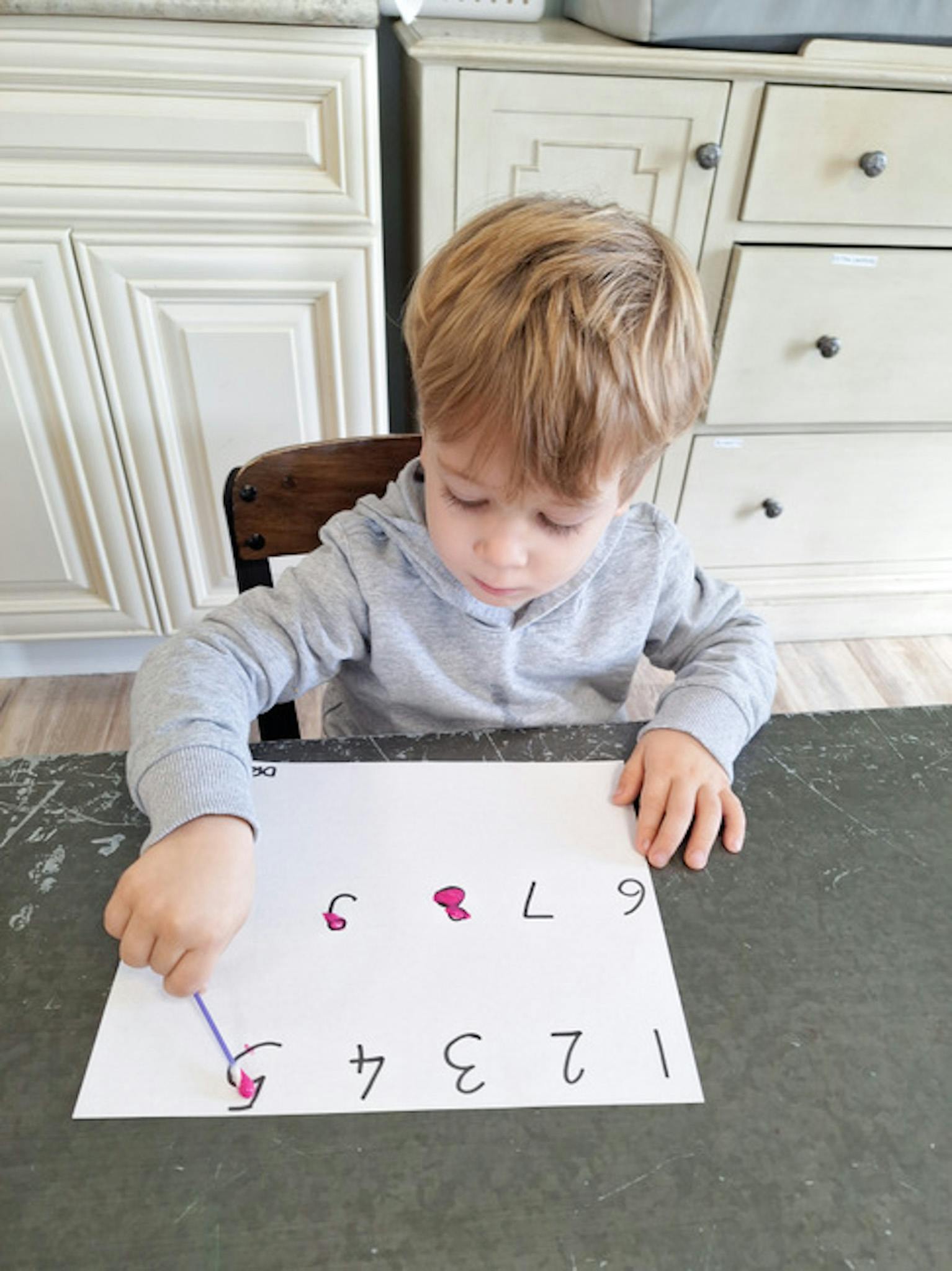 Child tracing numbers on a paper with a stylus